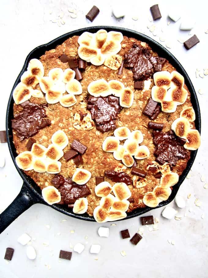 S’mores Oatmeal Cookie Skillet Cake recipe - This vegan and gluten free thick cookie cake is a hybrid between oatmeal bars and cookies, with chocolate chunks, marshmallows, oats, coconut flour and flavorful hints of cinnamon, nutmeg and ginger. A new spin on an old classic, perfect for summer or anytime of year! | veganchickpea.com