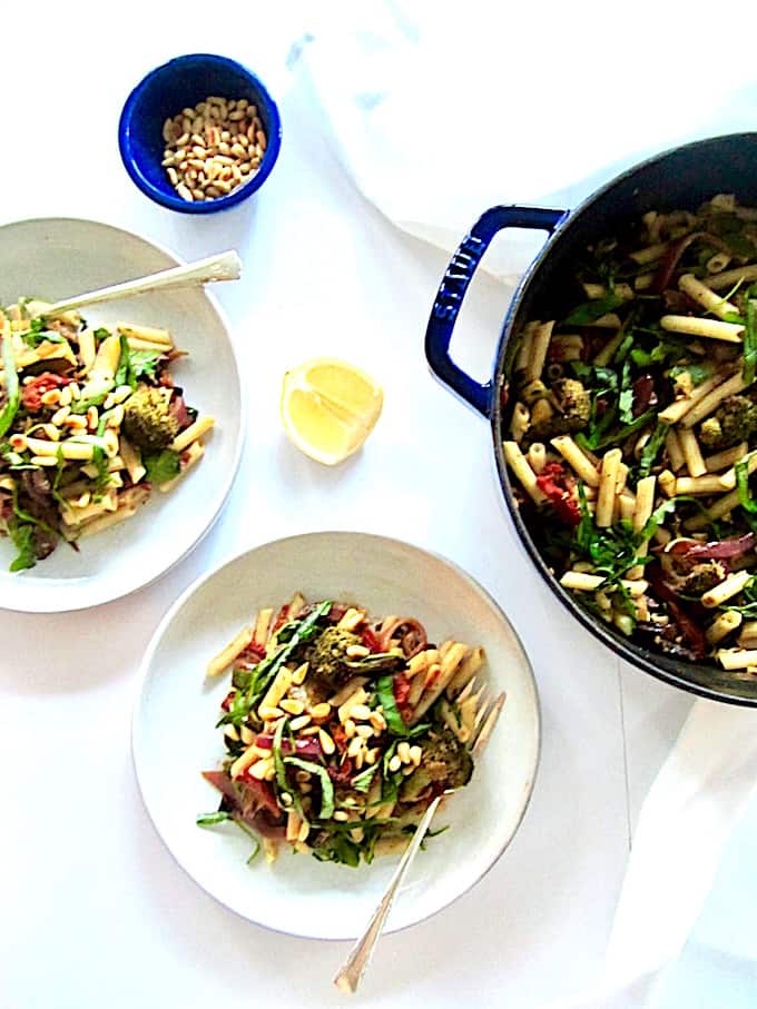 An easy, healthy, vegan and gluten free Italian penne pasta recipe featuring a garlic and balsamic roasted vegetable medley of broccoli, mushrooms, red onion, zucchini and chopped almonds for crunch. Toss it all together with sun-dried tomatoes, arugula, basil and pine nuts and you have a vibrant and colorful dish bursting with fresh flavor.