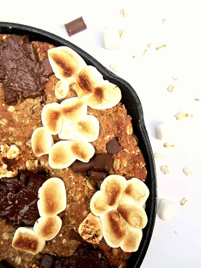 S’mores Oatmeal Cookie Skillet Cake recipe - This vegan and gluten free thick cookie cake is a hybrid between oatmeal bars and cookies, with chocolate chunks, marshmallows, oats, coconut flour and flavorful hints of cinnamon, nutmeg and ginger. A new spin on an old classic, perfect for summer or anytime of year! | veganchickpea.com